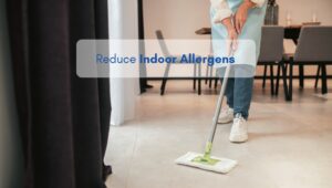 Person mopping the floor in an American-style living room to reduce indoor allergens like dust and pollen.