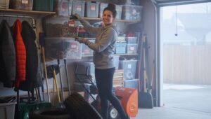 Person organizing storage bins in a clean and decluttered garage prepared for winter in a North American home.